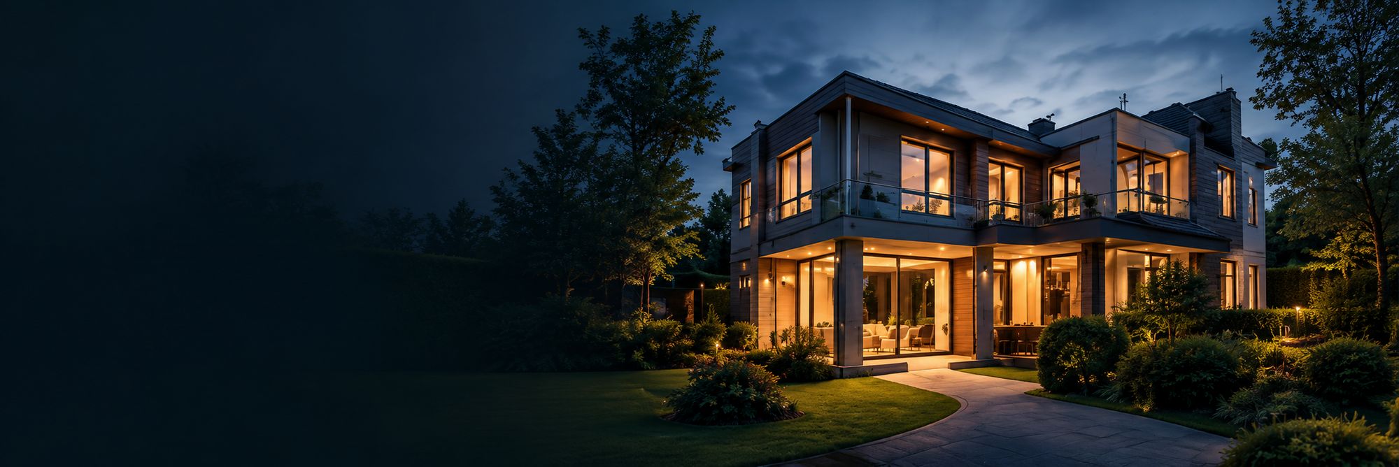 Vrijstaande woning in de avond, met verlichte ramen, gevelverlichting en verlichte tuinpaden.